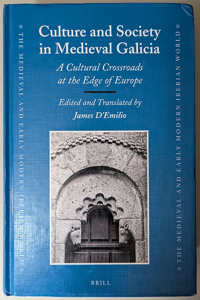 The blue cover of my edited volume, Culture and Society in Medieval Galicia, A Cultural Crossroads at the Edge of Europe, edited and translated by James D'Emilio. It features a photo of a detail of the narrow south doorway of the Romanesque church of San Paio de Diomondi. A semicircle is cut from the base of a plain tympanum and ringed with two concentric cusped arches. The tympanum rests on two corbels with bulls' heads and the outer arch of the portal has a precisely cut billeted hood.